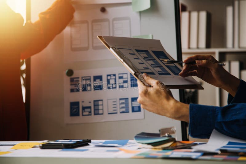 Close up ux developer and ui designer brainstorming about mobile app interface wireframe design on table with customer breif and royalty free stock photography