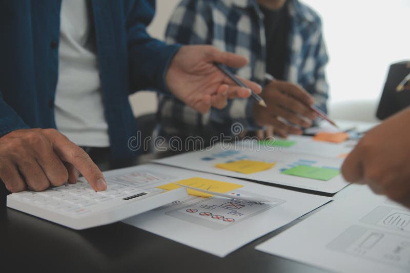 Close up ux developer and ui designer brainstorming about mobile app interface wireframe design on table with customer breif and stock photography