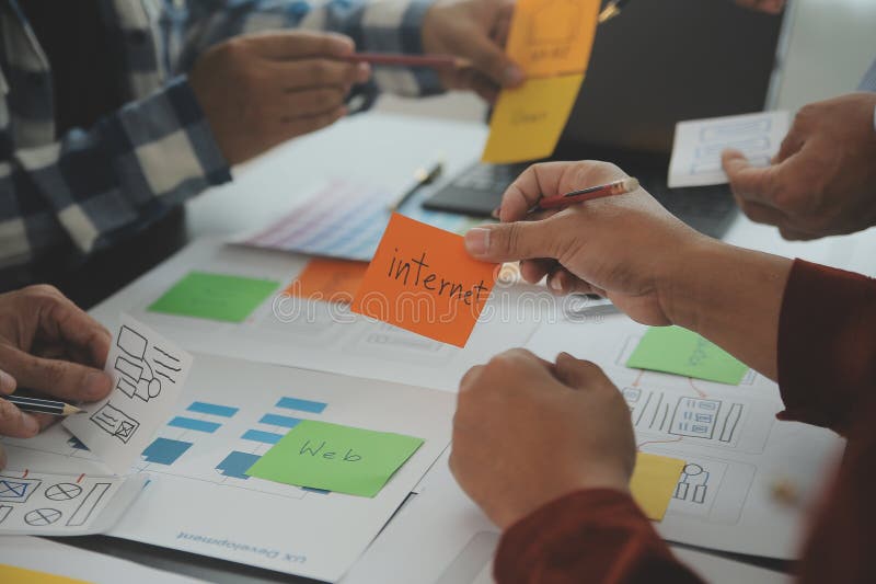 Close up ux developer and ui designer brainstorming about mobile app interface wireframe design on table with customer breif and royalty free stock photo