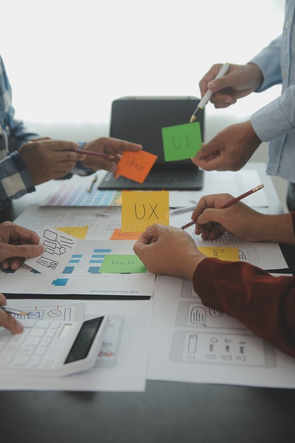 Close up ux developer and ui designer brainstorming about mobile app interface wireframe design on table with customer breif and stock image