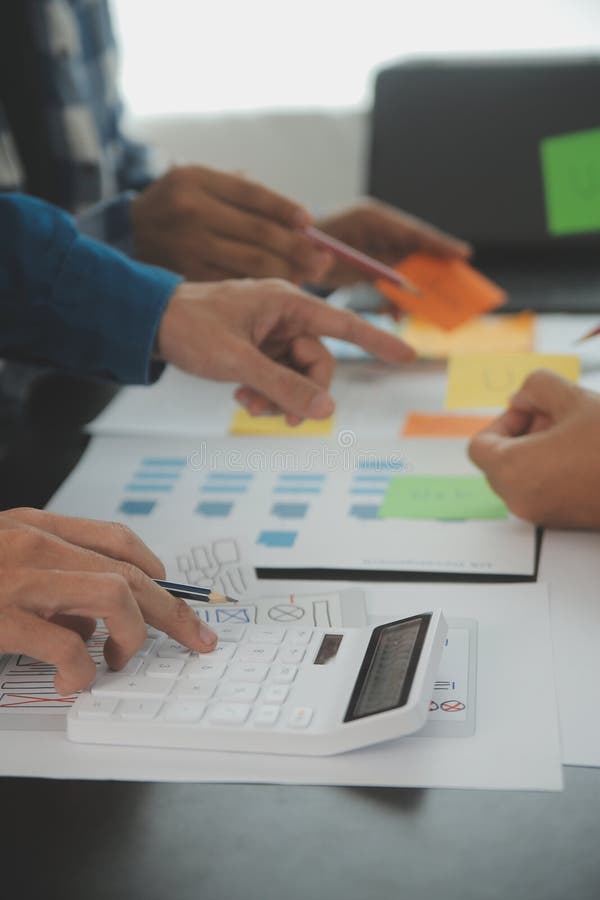 Close up ux developer and ui designer brainstorming about mobile app interface wireframe design on table with customer breif and stock photography