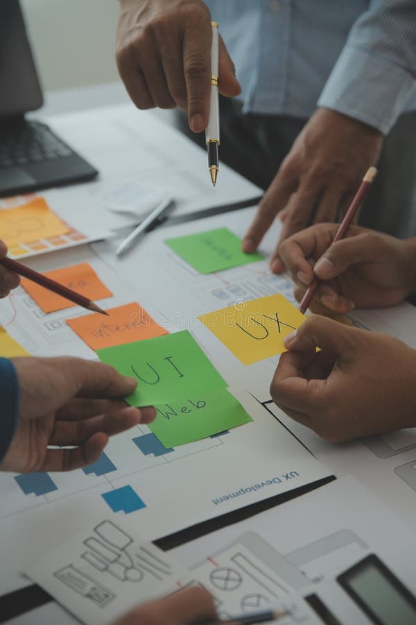 Close up ux developer and ui designer brainstorming about mobile app interface wireframe design on table with customer breif and royalty free stock photography