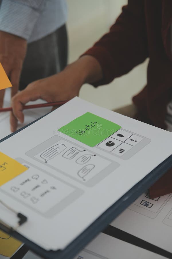 Close up ux developer and ui designer brainstorming about mobile app interface wireframe design on table with customer breif and royalty free stock image