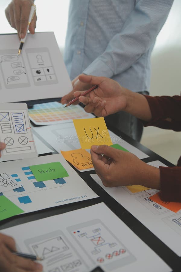 Close up ux developer and ui designer brainstorming about mobile app interface wireframe design on table with customer breif and royalty free stock photo