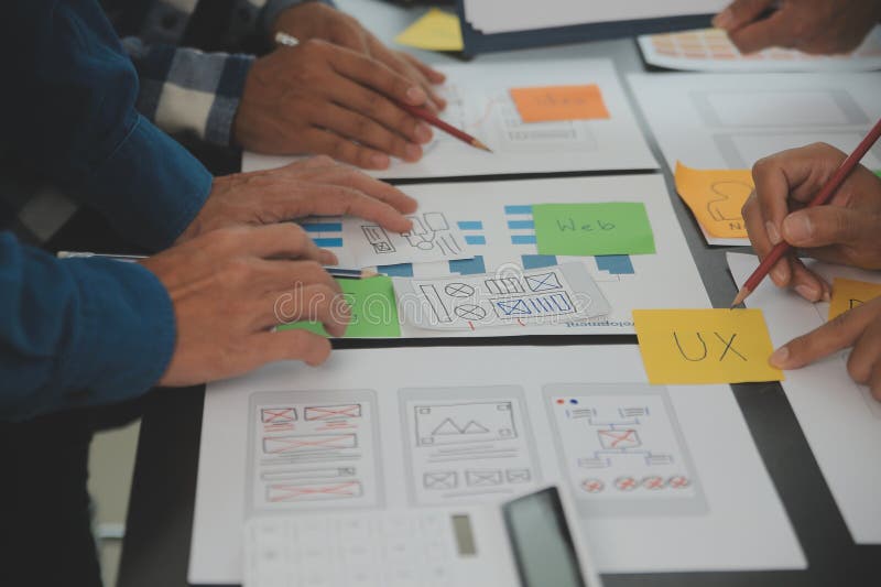 Close up ux developer and ui designer brainstorming about mobile app interface wireframe design on table with customer breif and royalty free stock images
