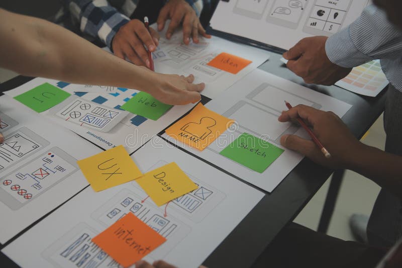 Close up ux developer and ui designer brainstorming about mobile app interface wireframe design on table with customer breif and stock image