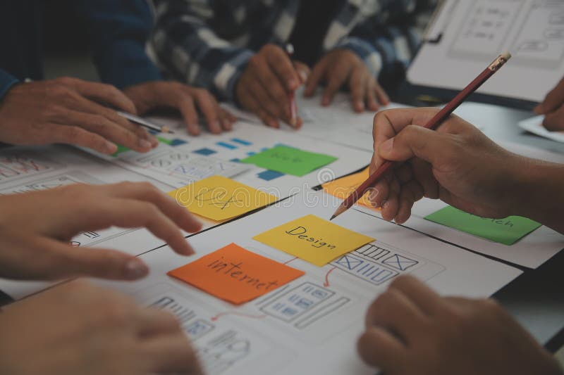 Close up ux developer and ui designer brainstorming about mobile app interface wireframe design on table with customer breif and stock photography