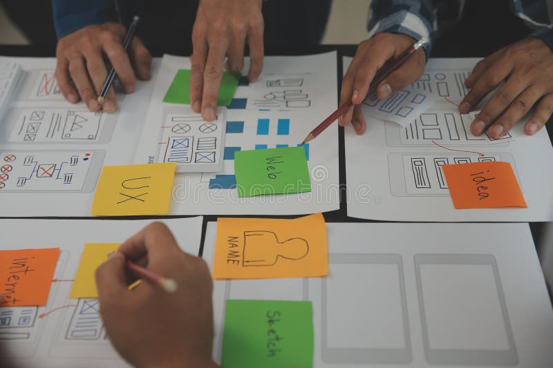 Close up ux developer and ui designer brainstorming about mobile app interface wireframe design on table with customer breif and royalty free stock photo
