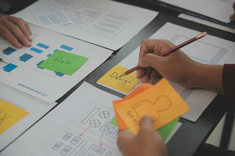 Close up ux developer and ui designer brainstorming about mobile app interface wireframe design on table with customer breif and royalty free stock photography