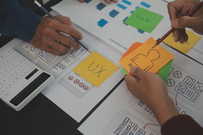 Close up ux developer and ui designer brainstorming about mobile app interface wireframe design on table with customer breif and royalty free stock images
