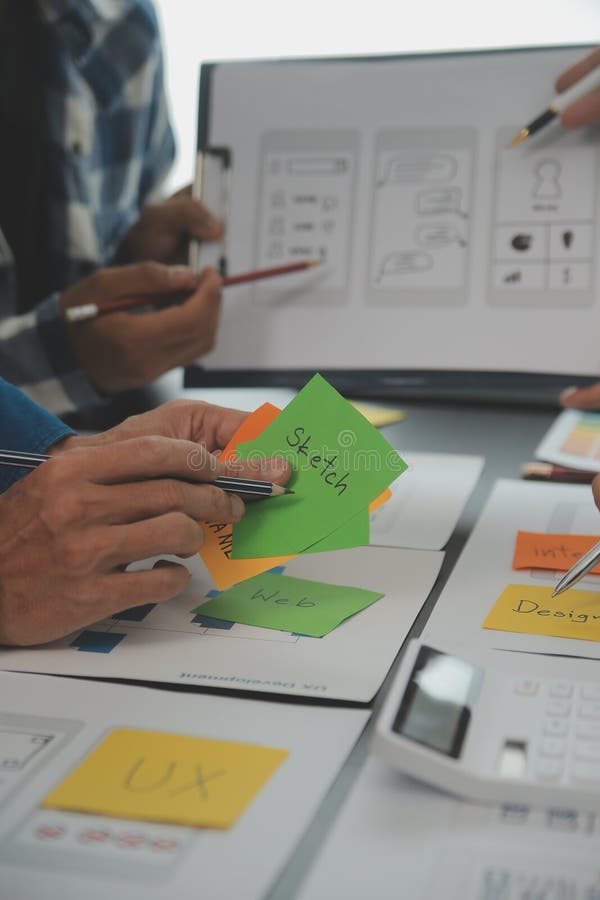 Close up ux developer and ui designer brainstorming about mobile app interface wireframe design on table with customer breif and royalty free stock photo