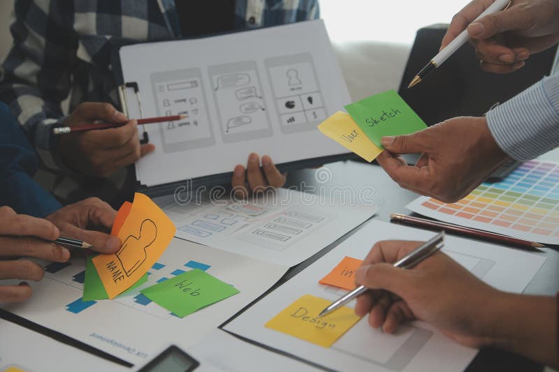 Close up ux developer and ui designer brainstorming about mobile app interface wireframe design on table with customer breif and royalty free stock photography