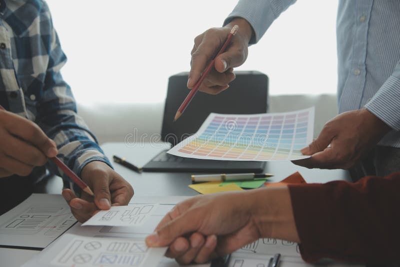 Close up ux developer and ui designer brainstorming about mobile app interface wireframe design on table with customer breif and royalty free stock photography