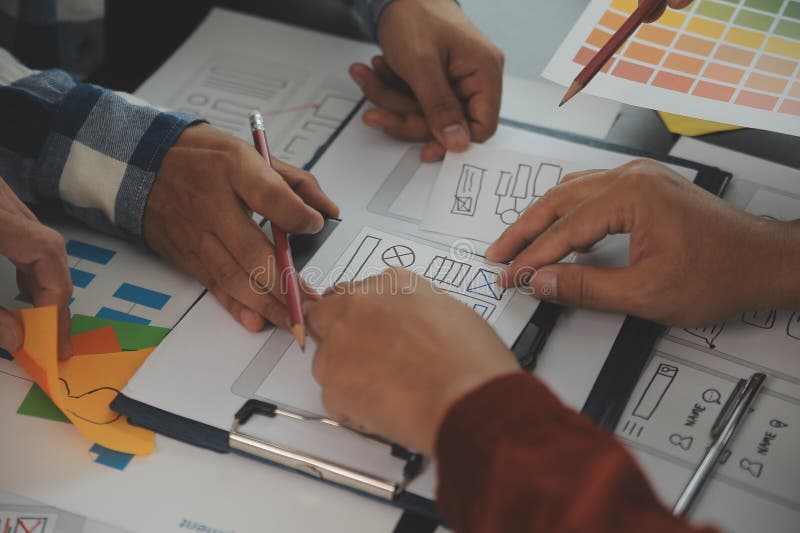 Close up ux developer and ui designer brainstorming about mobile app interface wireframe design on table with customer breif and royalty free stock photos