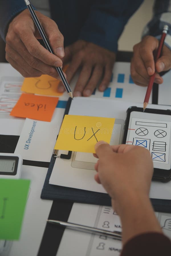 Close up ux developer and ui designer brainstorming about mobile app interface wireframe design on table with customer breif and royalty free stock images