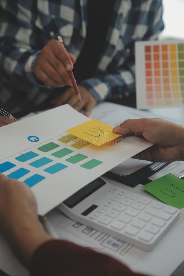 Close up ux developer and ui designer brainstorming about mobile app interface wireframe design on table with customer breif and stock image
