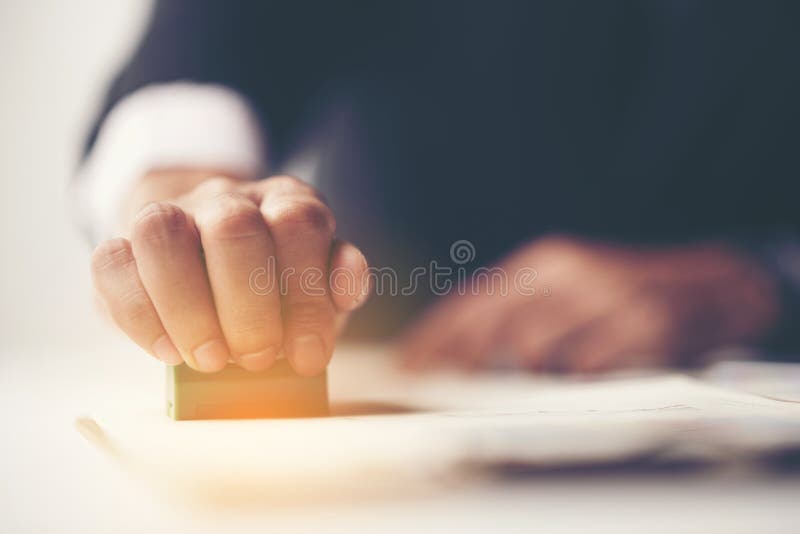 Close-up van de Hand van een Persoon het Stempelen met Goedgekeurde Zegel op Docu stock afbeelding Close-up van de Hand van een Persoon het Stempelen met Goedgekeurde Zegel op Docu stock afbeelding