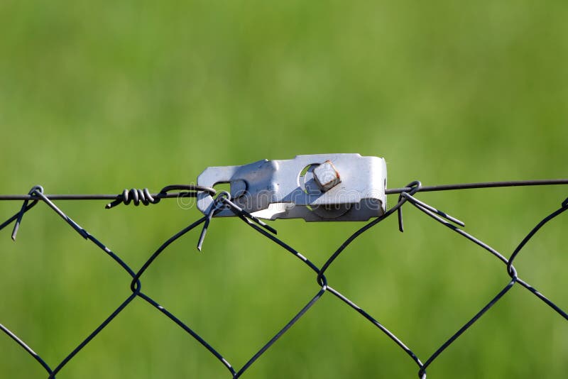Close-up van de het metaalspanner van de draadomheining de sterke grijze op lichtgroene achtergrond stock afbeelding Close-up van de het metaalspanner van de draadomheining de sterke grijze op lichtgroene achtergrond stock afbeelding