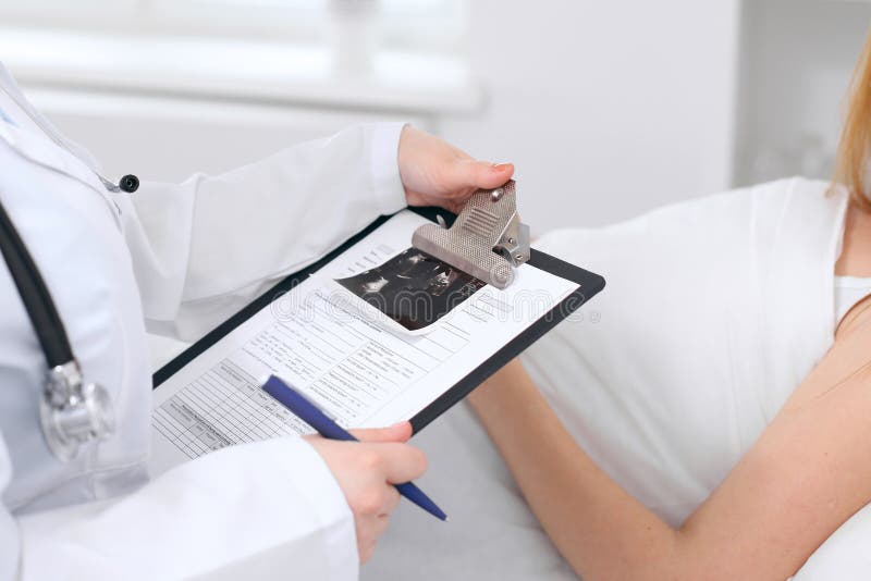 Close-up van een vrouwelijk aanvraagformulier van de artsenholding met echografie terwijl het raadplegen van patiënt royalty-vrije stock afbeelding Close-up van een vrouwelijk aanvraagformulier van de artsenholding met echografie terwijl het raadplegen van patiënt royalty-vrije stock afbeelding