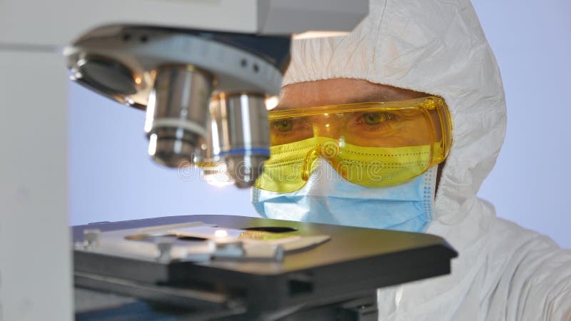 Close-up van een wetenschapper wordt geschoten die een glasplaatje met gevaarlijke bacteriën voorafgaand aan het onderzoeken ond stock fotografie Close-up van een wetenschapper wordt geschoten die een glasplaatje met gevaarlijke bacteriën voorafgaand aan het onderzoeken ond stock fotografie