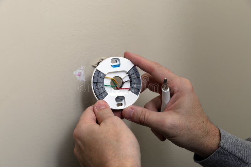 Close-up van Hand die het opzetten plaat voor moderne ronde thermostaat voor airconditioningseenheid installeren stock foto Close-up van Hand die het opzetten plaat voor moderne ronde thermostaat voor airconditioningseenheid installeren stock foto