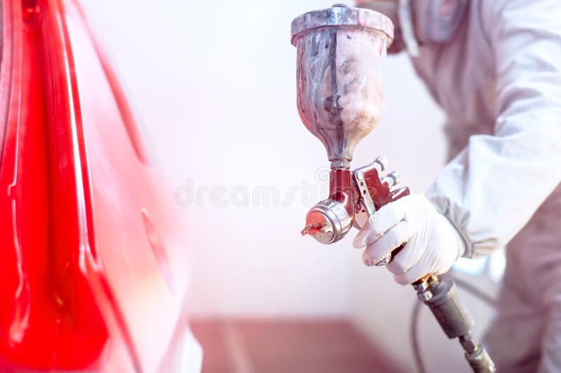 Close-up van spuitpistool met rode verf die een auto schilderen
