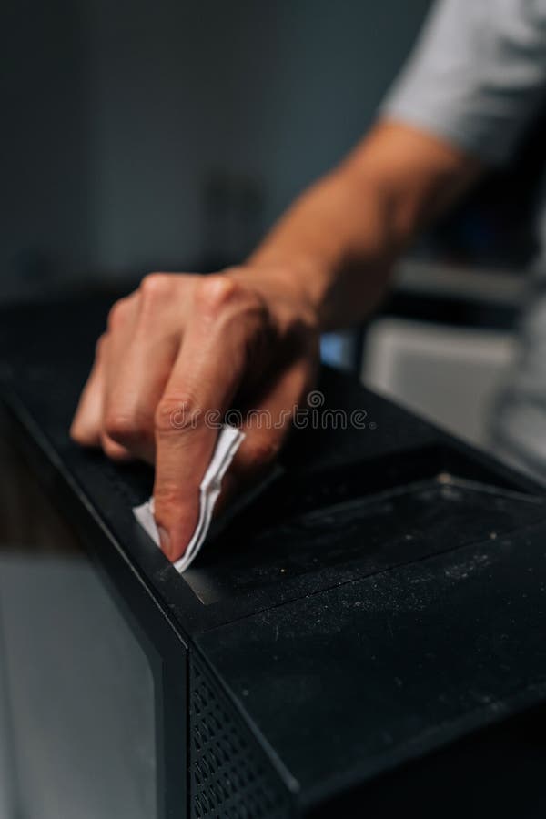Close-up vertical cropped shot of technician hand cleaning dust and grime from computer case with tissue, ensuring royalty free stock photography