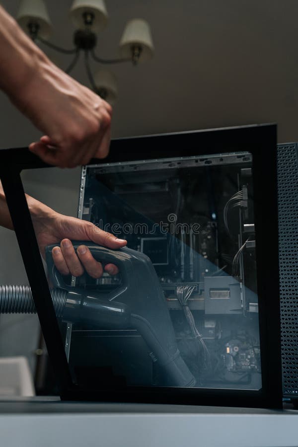 Close-up vertical shot of technician using vacuum cleaner to remove dust and debris from inside computer case royalty free stock photo