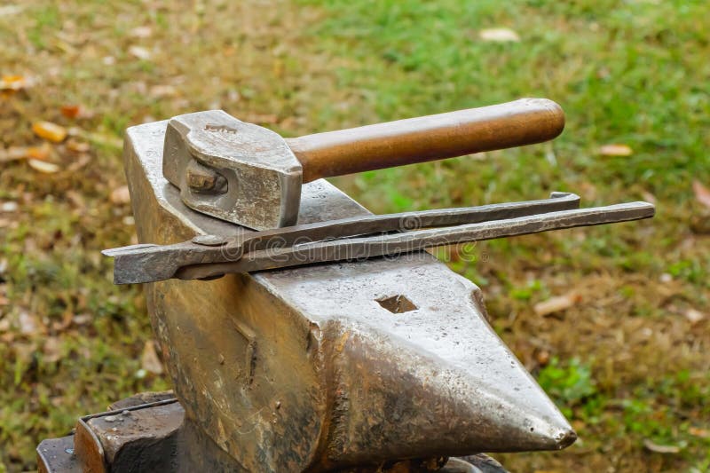 Blacksmith tools resting on an anvil in an outdoor workshop under sunlight, representing traditional craftsmanship royalty free stock image