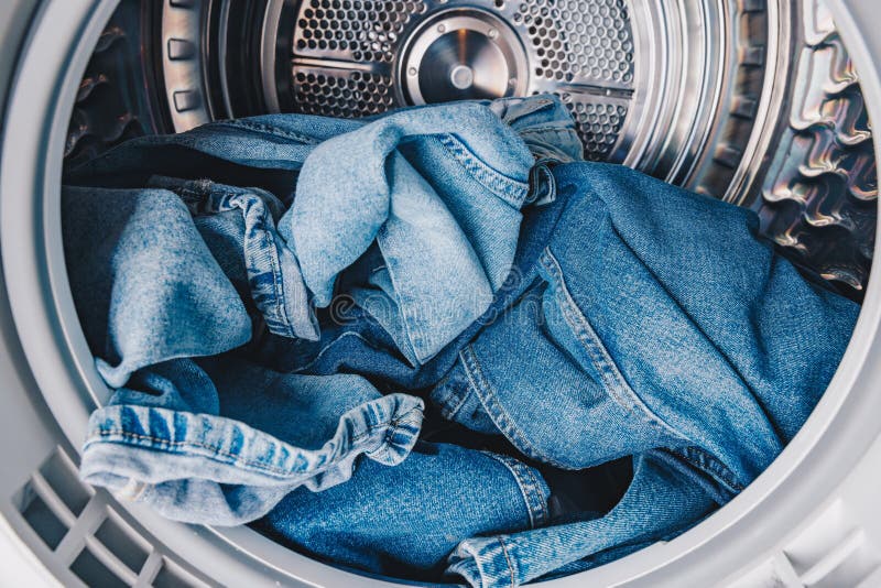 A Close-Up View of Blue Denim Jeans Spinning in the Drum of a Modern Washing Machine During a Laundry Cycle stock photos