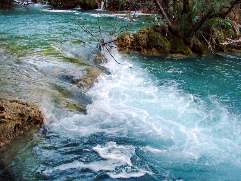 Fantastic panorama and natural scenery of forests, mountain rivers and waterfalls near Plitvice Lakes in Croatia. Close up view of boiling foam and numerous stream splash of mountain waterfalls underfoot against the backdrop of bright light of the morning sun.