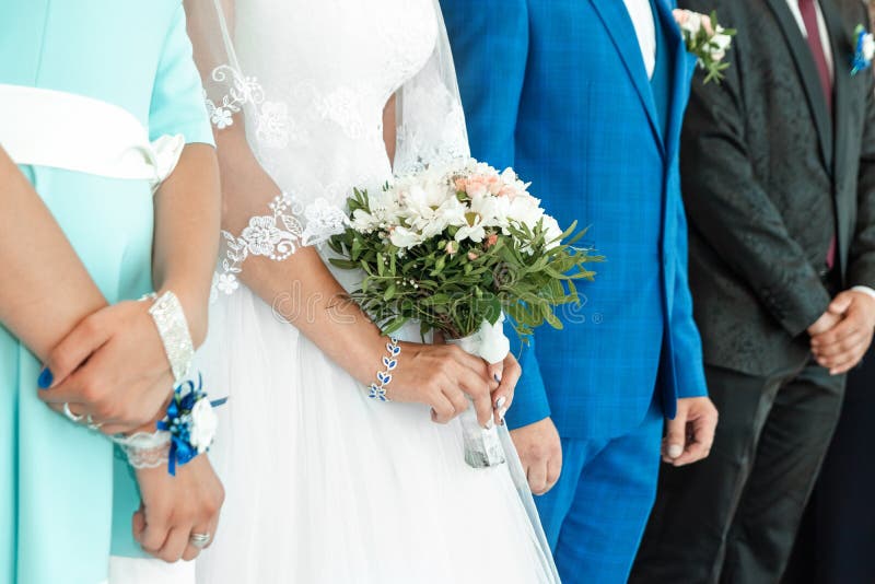 A close up view of a bride`s hands and bouquet with the bridal party in the background. Concept of marriage, family relationship, royalty free stock photography A close up view of a bride`s hands and bouquet with the bridal party in the background. Concept of marriage, family relationship, royalty free stock photography