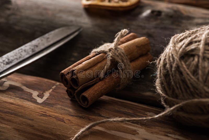 Close up view of cinnamon sticks, scissors, ball of thread on wooden background. stock photos
