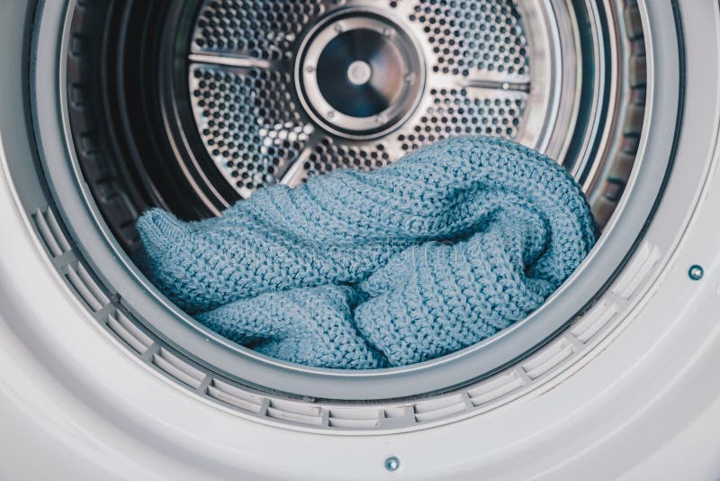 Close-Up View of a Cozy Blue Knitted Blanket Inside a Modern Washing Machine Drum, Highlighting Soft Textures and Efficient stock photo