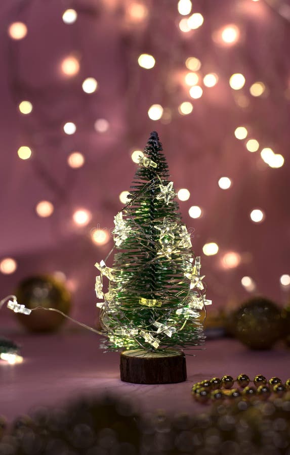 Closeup View of a Decorative Live MiniChristmas Tree in a Soft Bokeh of Garlands of Lights