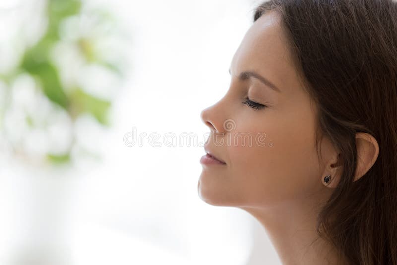 Closeup face attractive woman closed eyes daydreaming indoors