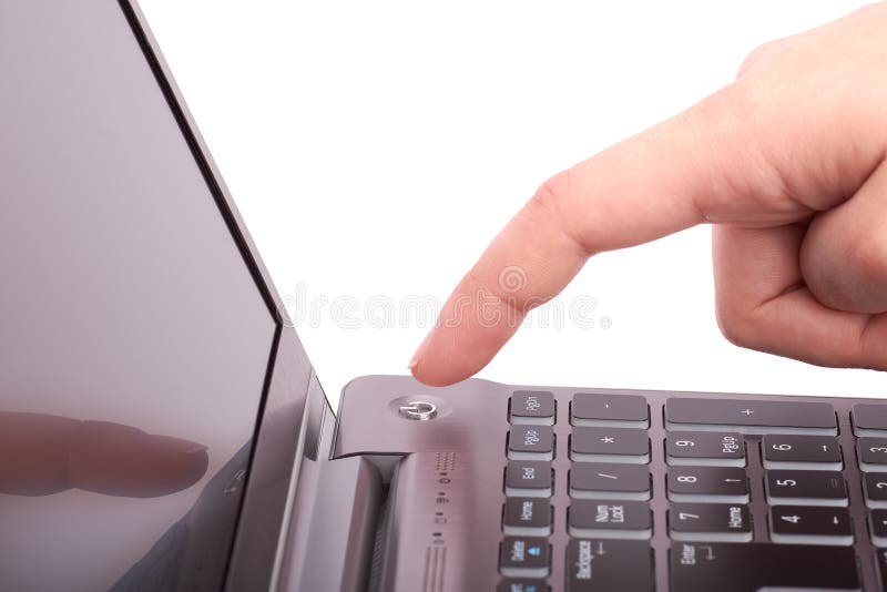Close-up view of female hand with index finger, pushing start button of laptop with black keyboard and display. Turns the notebook