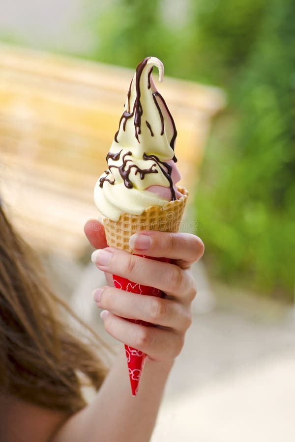 Close-up view of girl`s hand holding ice cream with chocolate to