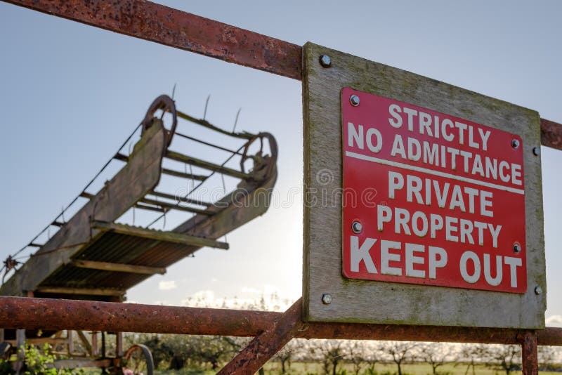 Close-up view of an improvised Keep Out sign attached to a rusting farm gate entrance.