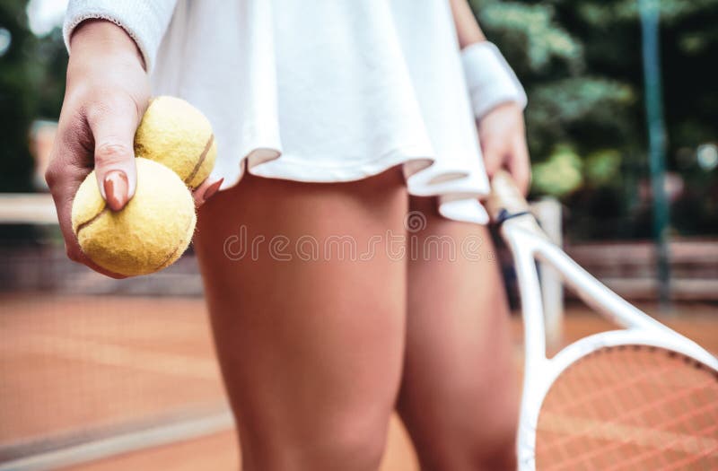 legs of young girl in a tennis court with ball and racket