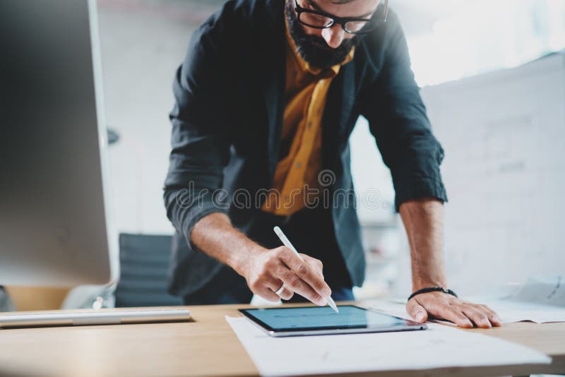 Close up view of man in formal wear working with portable tablet computer and drawings digital plans in modern lightful