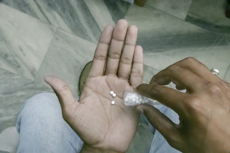 Close-up view of man hand pouring homeopathic pills from the bottle on hand. Top view image of male hands taking daily dose of royalty free stock photos Close-up view of man hand pouring homeopathic pills from the bottle on hand. Top view image of male hands taking daily dose of royalty free stock photos