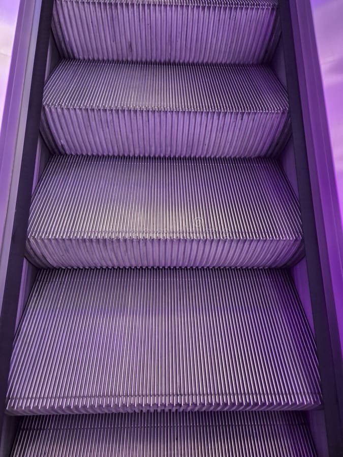 A close-up view of metallic escalator steps with a purple hue, creating a modern and stylish atmosphere. Ideal for architectu stock photos