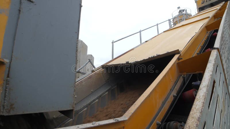 Close-up view of conveyor belt of heavy-duty equipment carrying sand