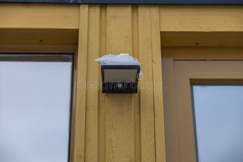 Close up view of outdoor led waterproof solar lamp with motion sensor covered with snow.