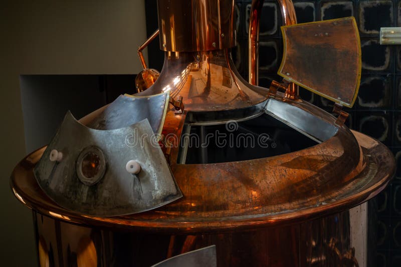Traditional Copper Brewing Kettle with Open Hatch in Czech Republic. Close-up view of a shiny copper brewing kettle with an open hatch and metallic fittings inside a traditional brewery. The image highlights the classic design and craftsmanship of beer brewing equipment, reflecting warm tones and industrial details in Czech Republic