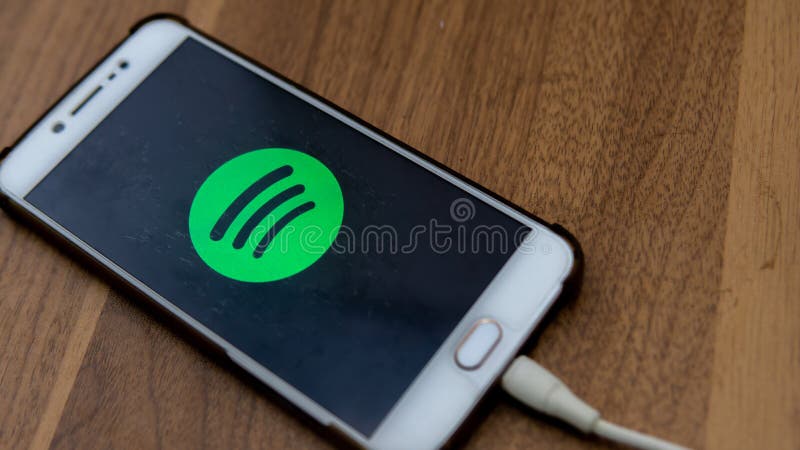 The close up view of the Spotify logo display on an Android phone with wooden table background stock photos