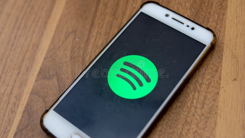 The close up view of the Spotify logo display on an Android phone with wooden table background royalty free stock images