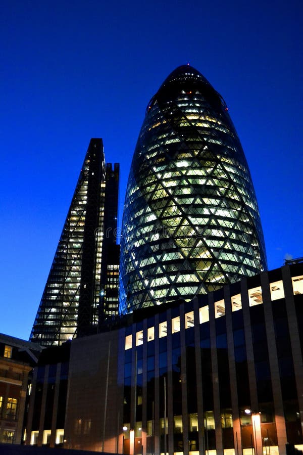 Close-up view to a Gherkin cucumber architecture and Cheesegrater skyscrapers by night.