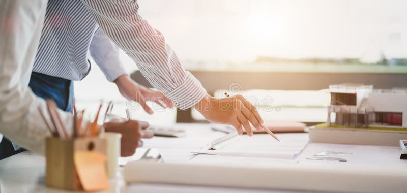 Close-up view of young professional architect and engineer working together on construction plans in modern office royalty free stock image